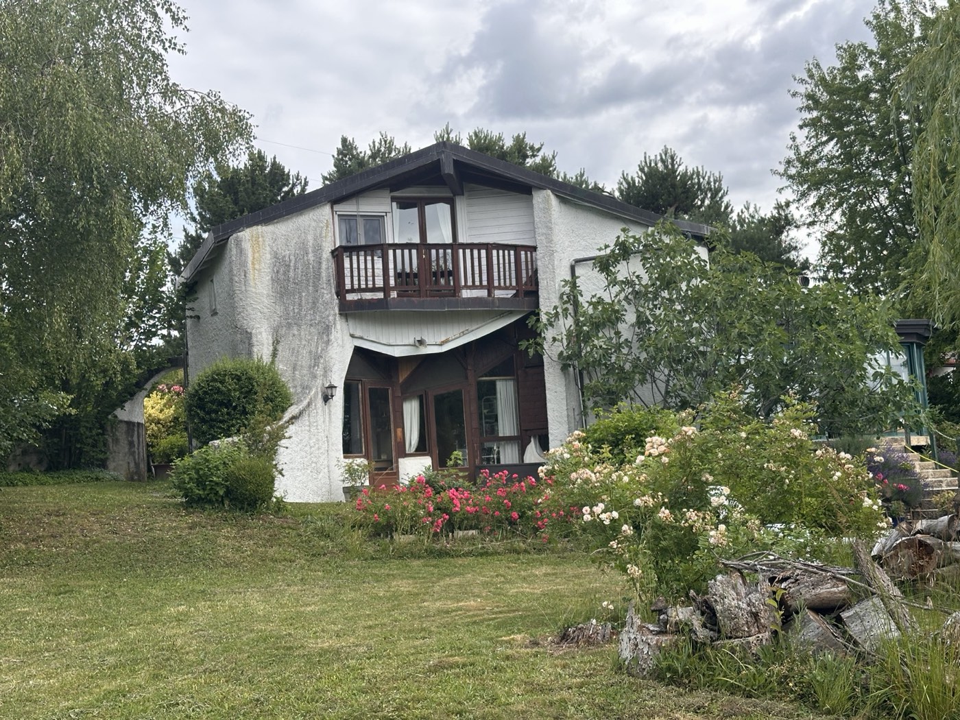 Balcon de bois et façade de la maison dans la végétation